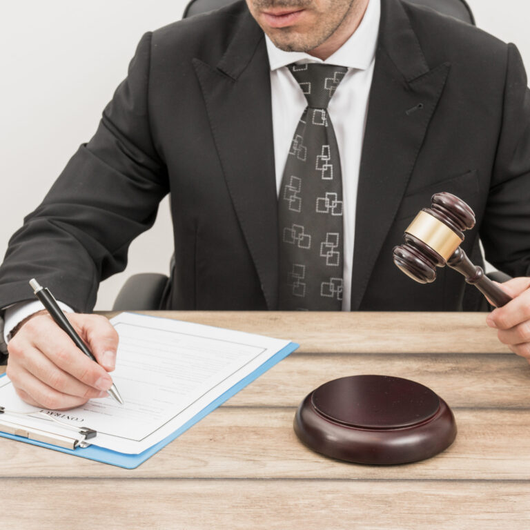 Lawyer in a suit filling out estate planning documents with a gavel on the table, symbolizing legal compliance and guidance for wills and trusts in Kingwood.